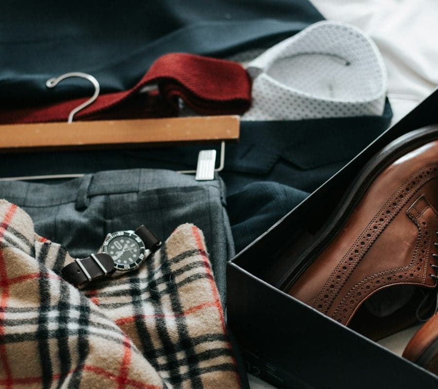 Grey suit trousers, brown brogues, a watch and a checked scarf laid out together